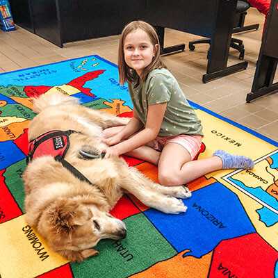 Broach School South Student Brushing a Service Dog on the Floor